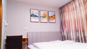 A bedroom with a bed, a chair, a desk, and three framed pictures on the wall. - Yiting Hotel Loudi (Loudi)