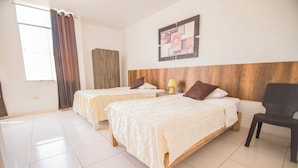 Een hotelkamer met twee bedden, een houten hoofdeinde, een kunstwerk aan de muur en een stoel.
