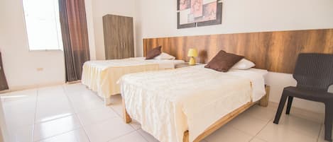 A hotel room with two beds, a wooden headboard, a wall art piece, and a chair.
