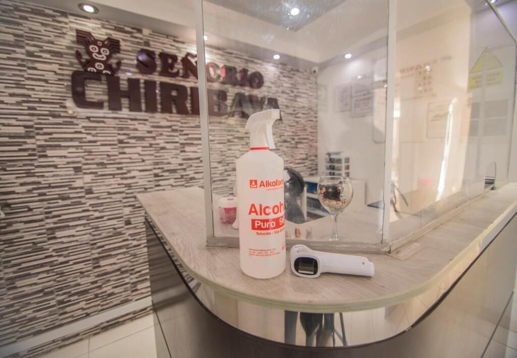A reception area with a textured wall, a bottle of alcohol sanitizer, and a hairdryer on a glass counter.