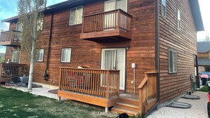 Una casa a due piani in legno, con un balcone, un portone d'ingresso e un piccolo portico.