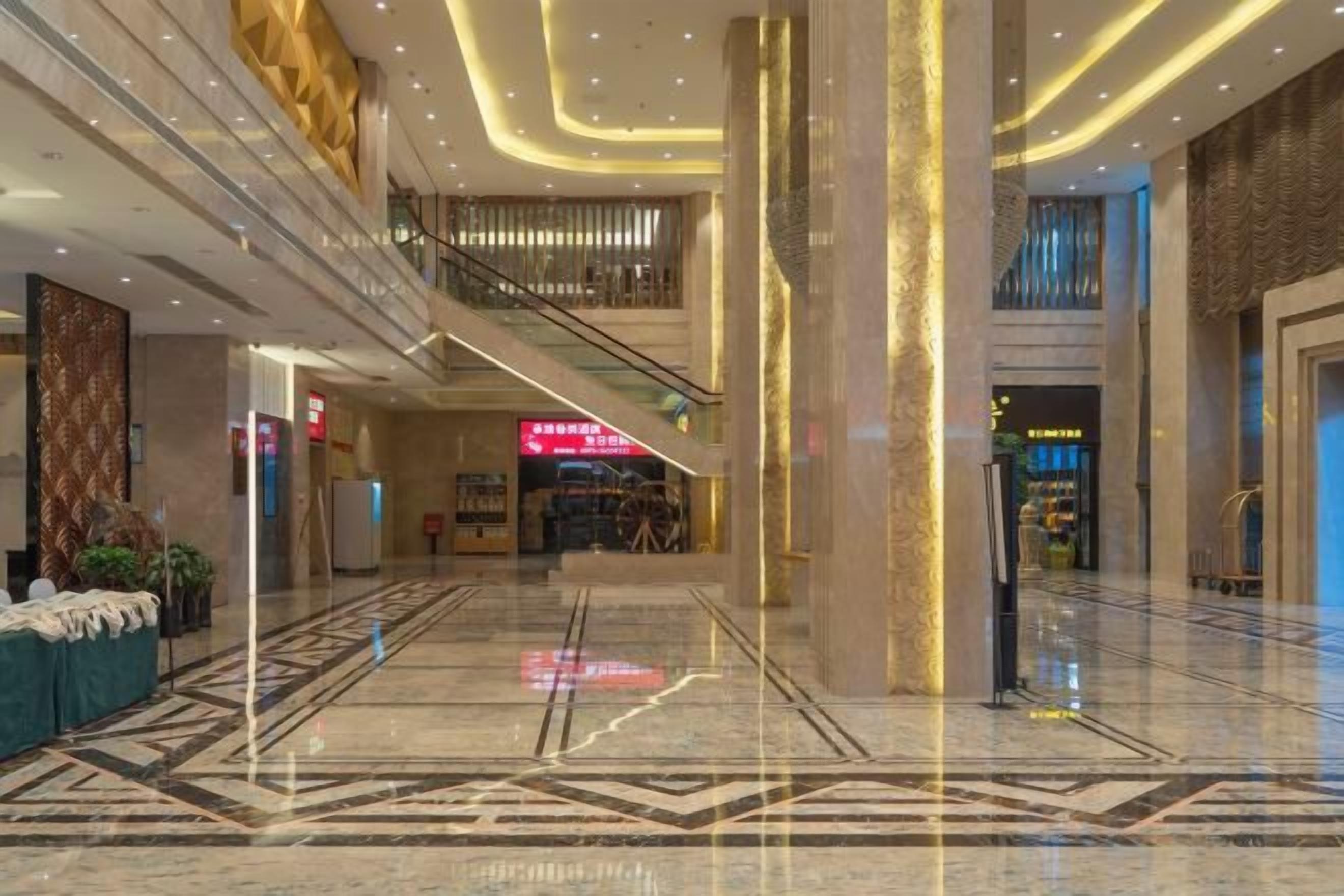 A spacious lobby with a marble floor, a staircase, and a reception desk.