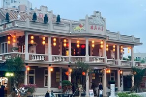 Un edificio de dos pisos con balcón, columnas y un letrero con un símbolo de león.