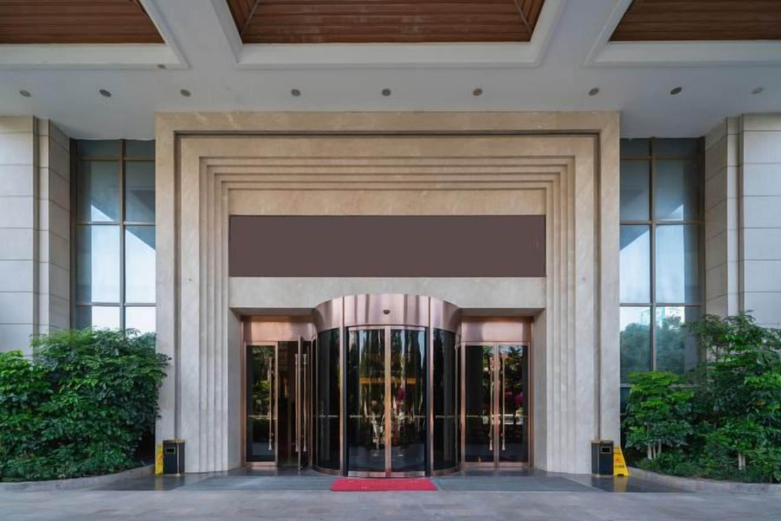 A hotel entrance with a revolving door, large windows, and a red carpet.