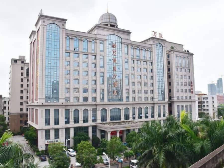 A multi-story hotel with a prominent central glass facade and a dome on top.
