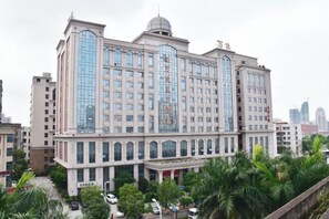 Un hotel de varios pisos con una fachada central de vidrio destacada y una cúpula en la parte superior.
