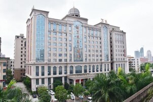 Un hotel de varios pisos con una fachada central de vidrio destacada y una cúpula en la parte superior.