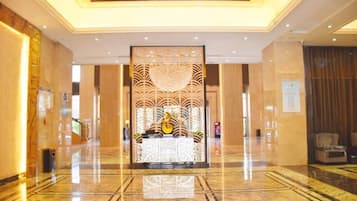 A hotel lobby with a reception desk, a decorative partition, and a seating area.