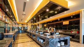 A modern hotel lobby with a long reception desk, seating area, and a large mirror.