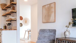 A modern living room with a grey armchair, a glass coffee table, and a wooden console table. - Modern Loft in Historic Birdtown - Unit 6 (Lakewood)
