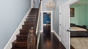 A staircase leading to a bedroom with a bed, a chandelier, and a door.