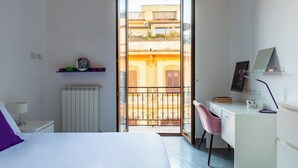 A bedroom with a bed, a desk with a chair, a radiator, and a view of a balcony with a railing. - Ferdinando Art House by Wonderful Italy (Naples)