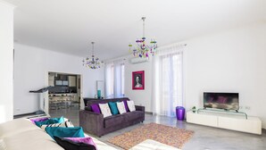 A modern living room with a sofa, a couch, a TV, and a kitchen in the background. - Ferdinando Art House by Wonderful Italy (Naples)
