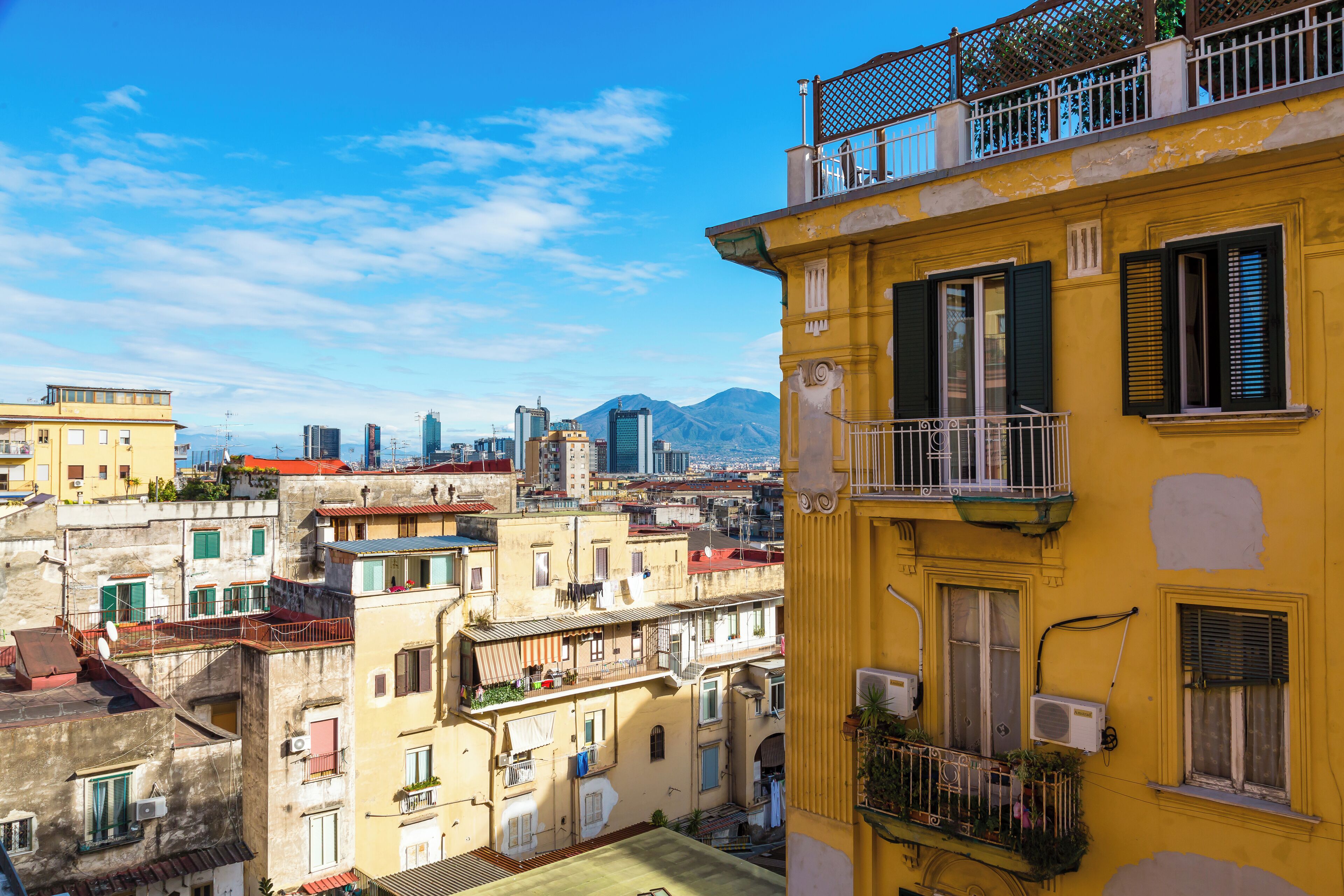 A yellow building with balconies and air conditioning units.