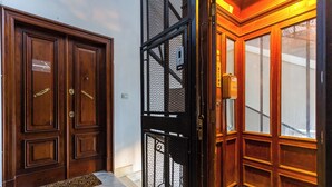 A set of wooden double doors with a metal security gate, a doormat, and a small step leading to a tiled floor. - Ferdinando Art House by Wonderful Italy (Naples)