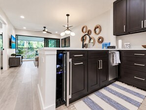 Una cocina moderna con armarios oscuros, lavavajillas integrado y un amplio ventanal con vistas al exterior.