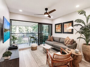 A modern living room with a sofa, coffee table, chairs, and a TV.