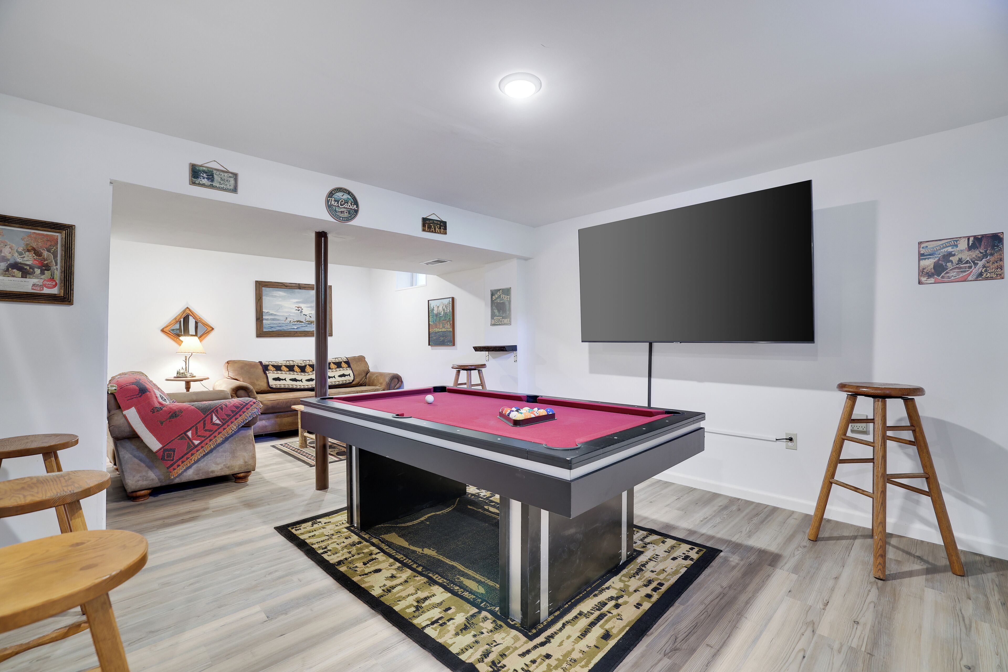 A pool table in a room with a sofa, armchairs, and a television.