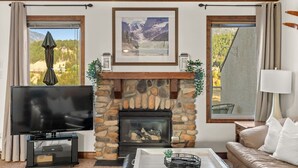 A living room with a stone fireplace, a television, and a sofa.