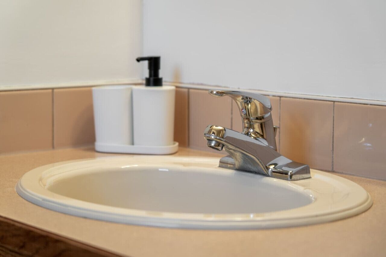 A bathroom sink with a chrome faucet and a soap dispenser.