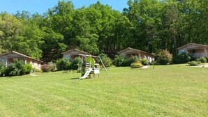 A campground with multiple cabins, a playground, and a grassy field.