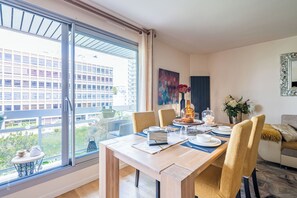 Spisestue med stort vindue, et bord dækket til fire og udsigt til en bygning.