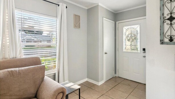 A room with a beige sofa, a door with a decorative glass panel, and a wall-mounted decorative piece.