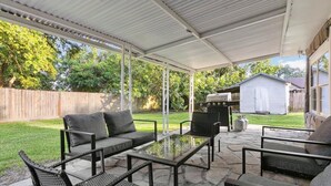 A covered patio area with a sofa, chairs, and a table.