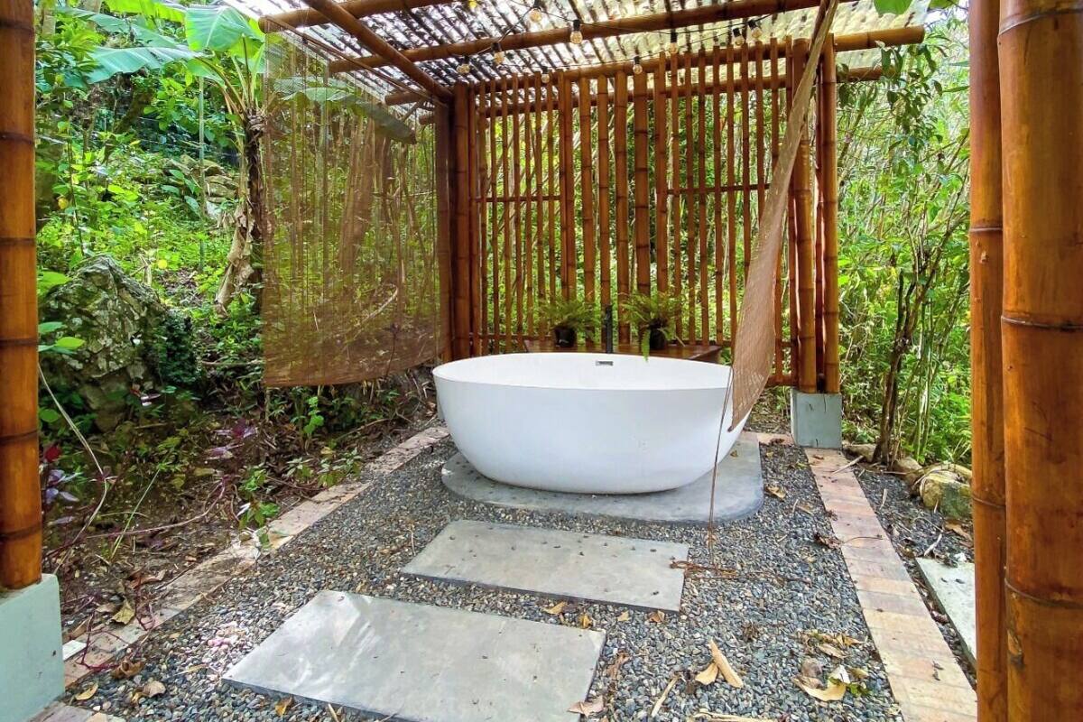Un espace de bien-être doté d’une grande baignoire blanche, d’éléments en bambou et d’un environnement naturel.
