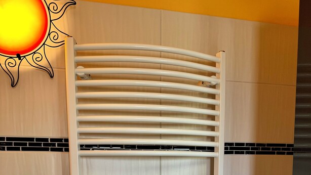 A white radiator with a curved design, mounted on a tiled wall with a black and white tile border. - High-quality vacation home near Potsdam, within walking distance of the water. Pet friendly! (Werder (Havel))