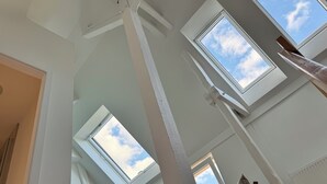 Een kamer met dakramen, een houten stoel en een radiator.