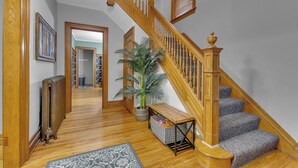 Eine Holztreppe mit einer Sitzbank, einem Heizkörper und einem Blumentopf in einer Diele.