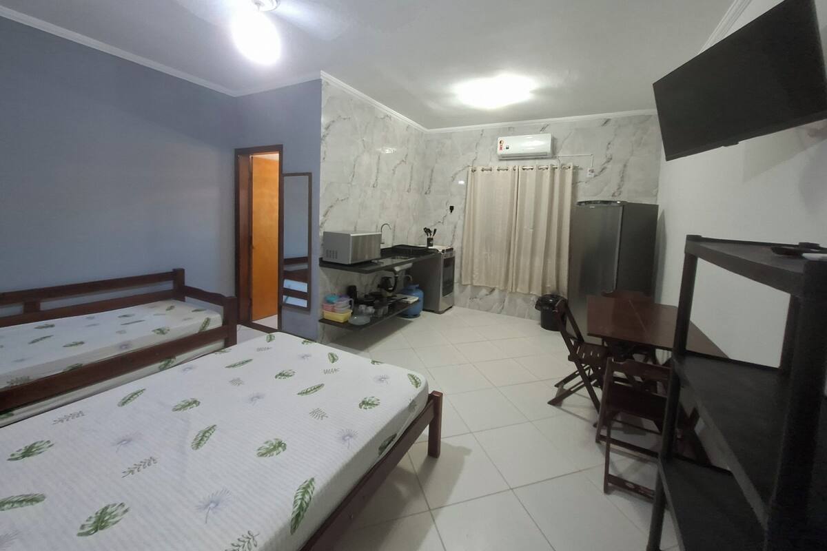 Een slaapkamer met een bed, bureau, stoel, televisie, kledingkast en een badkamer met douche en toilet.