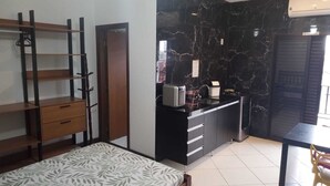 A compact bedroom with a bed, a wardrobe, a small kitchenette, and a bathroom. - Dell Mar Rentals - Flats and Apartments for Season - Ubatuba (Ubatuba)