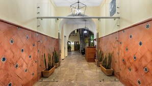 A hallway with tiled walls, potted plants, and a staircase in the background. - Casa Haus Hotel Puebla Centro Histórico (Puebla)