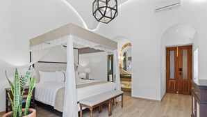 A bedroom with a four-poster bed, a bench, a potted plant, and a wooden cabinet. - Casa Haus Hotel Puebla Centro Histórico (Puebla)