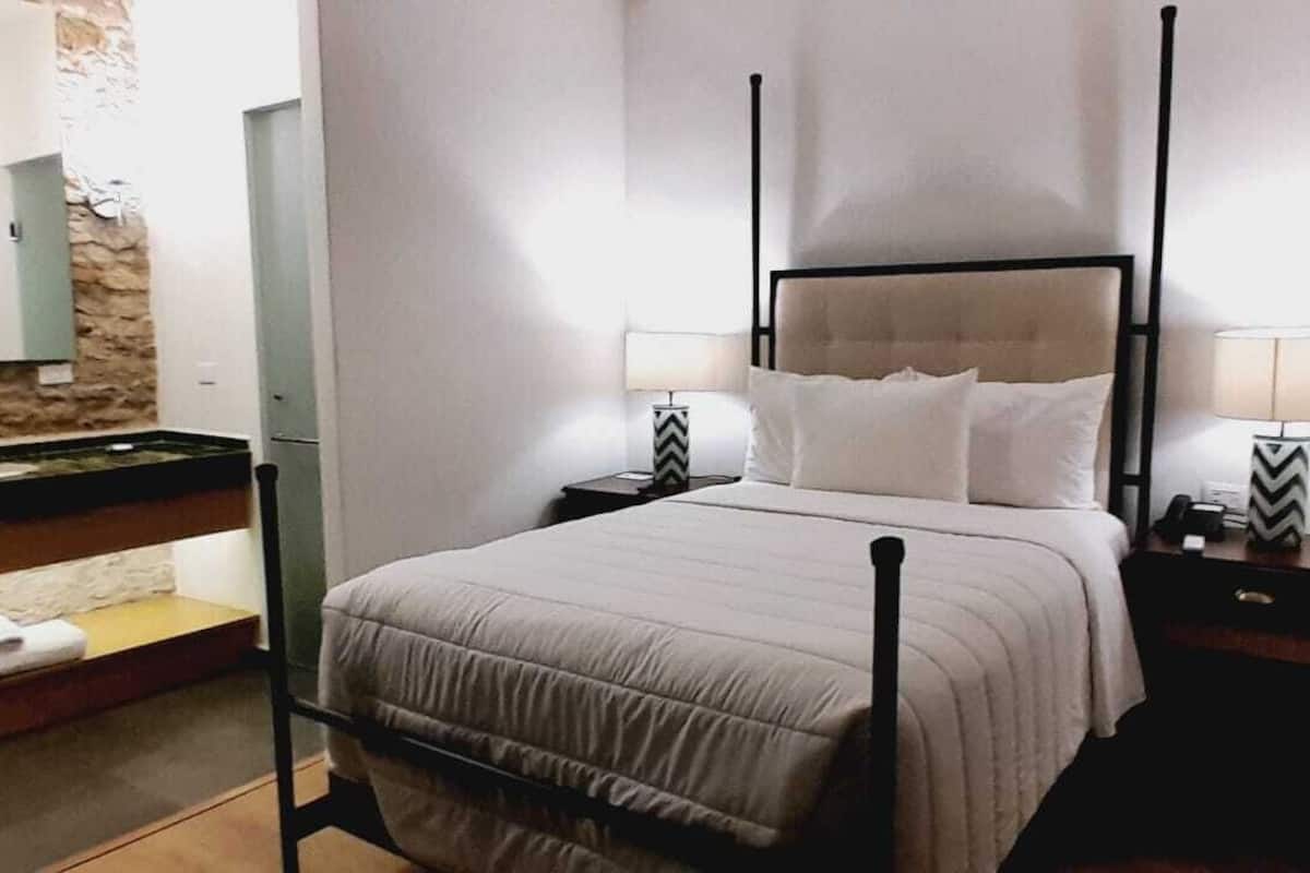 A neatly arranged bedroom with a bed, bedside tables, and a mirror.