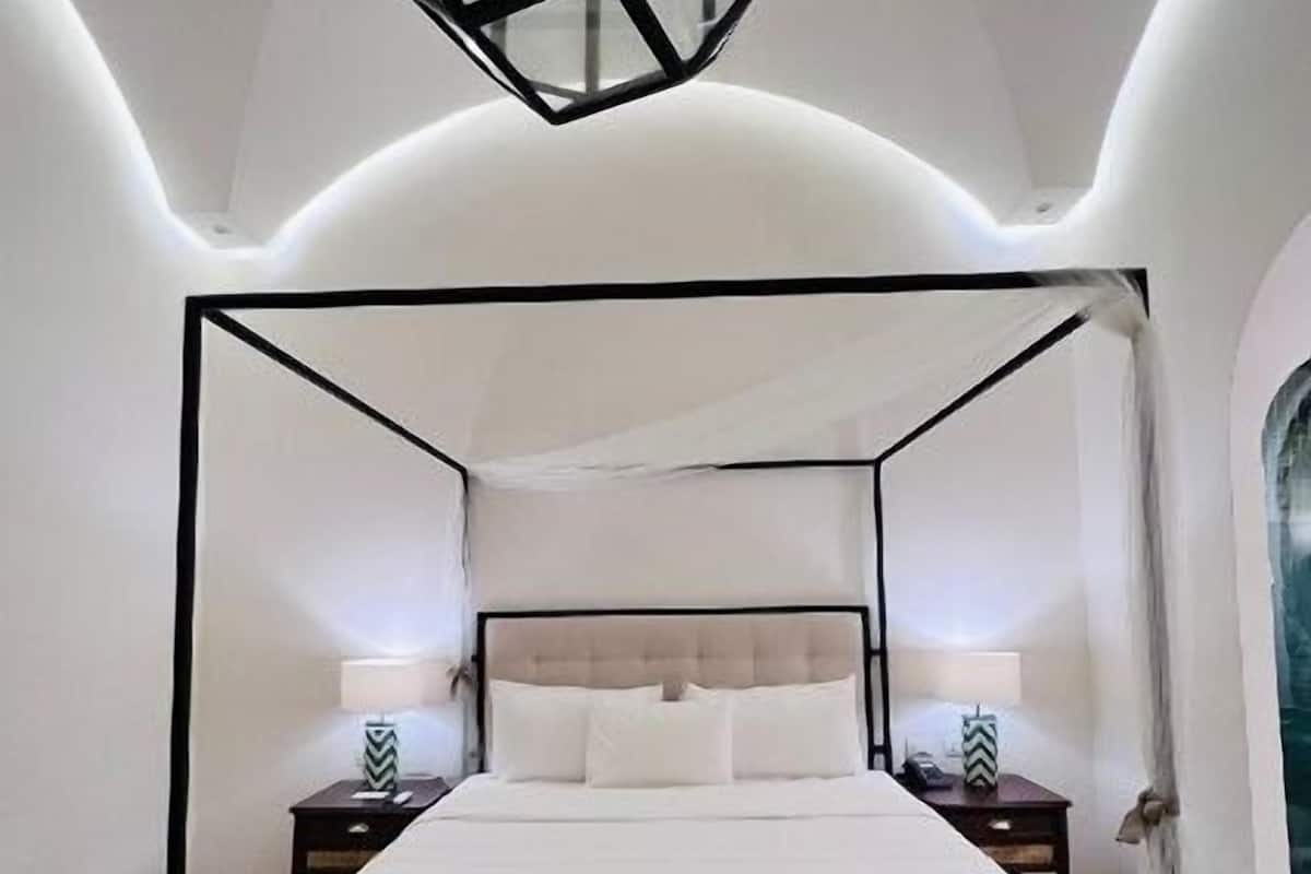 A modern bedroom with a four-poster bed, bedside tables, and a hanging light fixture.