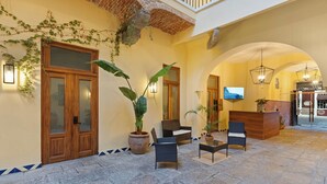 A lobby with a reception desk, seating area, and a TV screen. - Casa Haus Hotel Puebla Centro Histórico (Puebla)
