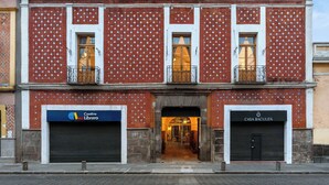A building with a red brick facade, two visible balconies, and storefronts for 'Centro Libero' and 'Casa Bacuza'. - Casa Haus Hotel Puebla Centro Histórico (Puebla)