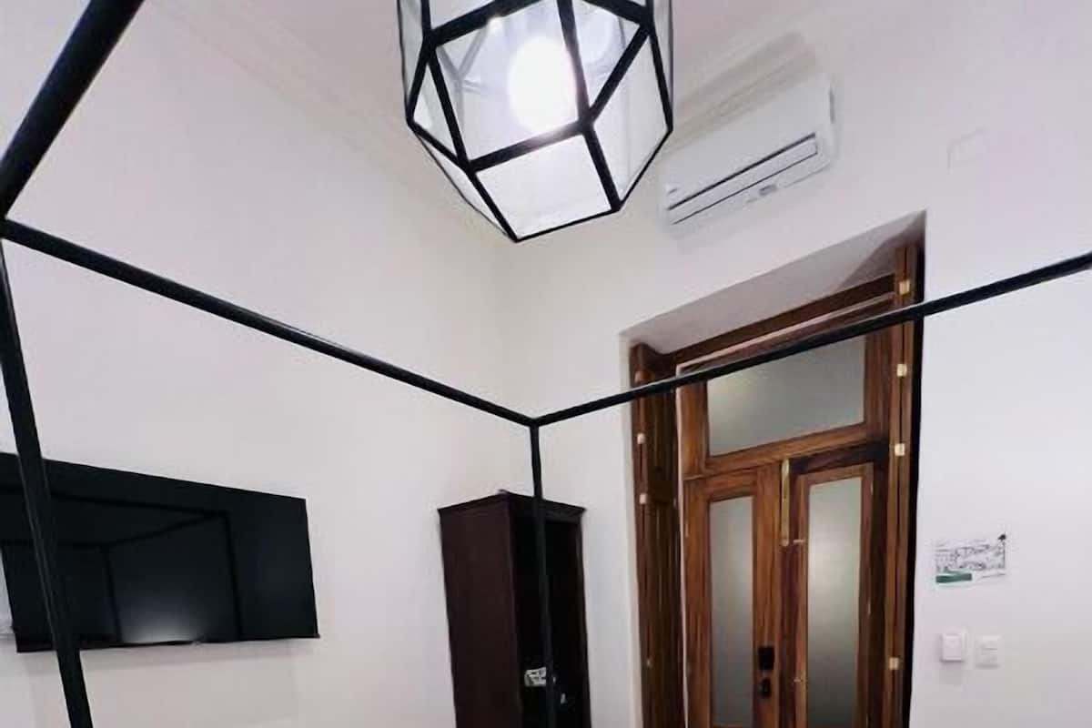 A bedroom with a bed, a wardrobe, a television mounted on the wall, and a door with a mirror.