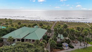 Un hôtel situé en bord de mer, doté d’un toit végétalisé, d’une promenade en bois menant à la plage et de palmiers.