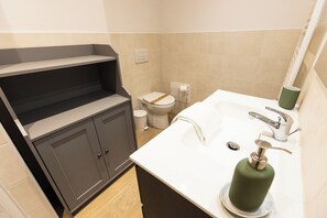 A modern bathroom with a toilet, sink, and storage cabinet.