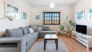 A modern living room with a grey sofa, a coffee table, a TV on a white stand, and artwork on the walls. - Dream Views of Porto - Private Apt in Gaia by Lisbeyond (Vila Nova de Gaia)