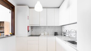 A modern kitchen with white cabinets, a marble backsplash, and a wooden floor. - Dream Views of Porto - Private Apt in Gaia by Lisbeyond (Vila Nova de Gaia)