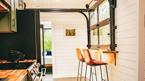 A modern kitchen with wooden cabinets, a built-in oven, and a bar area with stools. - Unique Cabin on the Beechfork River, nestled in the heart of the Bourbon Trail  (Springfield)