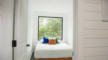 Una habitación pequeña con una cama, un ventanal y una puerta.