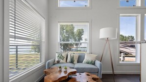 A modern living room with a grey sofa, wooden coffee tables, and a floor lamp. - Site 93 @ Peninsula point (Kerens)