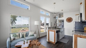 A modern kitchen with a central island, large windows, and a view of the outdoors. - Site 93 @ Peninsula point (Kerens)