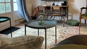 Un salon avec une grande fenêtre, un téléviseur à écran plat, une petite table ronde et un canapé.